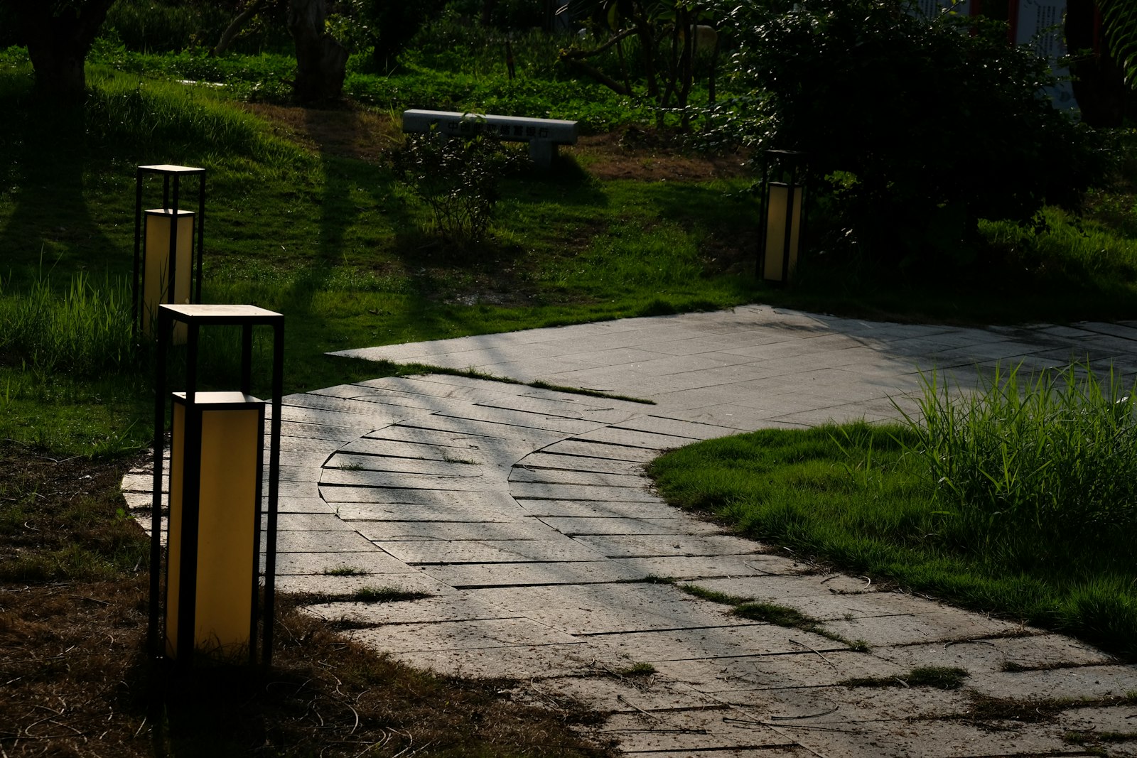 A bollard light beside a paved path through a garden